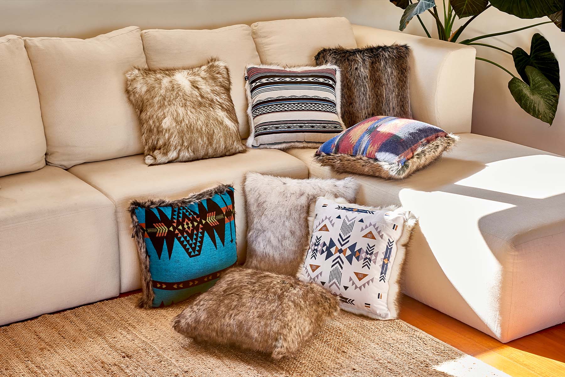 faux fur throw pillows on and around creme colored couch