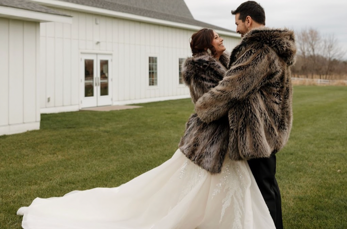 A bride and groom wear grey wolf Spirithood faux fur coats.