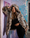 A Woman wearing SpiritHoods Best Selling Wolverine inspired Hooded Faux Fur Coat with the hood up, as she leans against a whimsical purple wall with cut out glass shapes and art. 100% Vegan Fashion Brand SpiritHoods Faux Fur Coats for Women and Womens Fake Fur Jackets