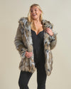 A curvy, flirty, smiling blonde girl rocking a realistic Hooded Wolverine fur coat with the hood down, one hand holding the top lapel and the other holding the lower lapel.