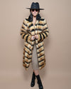 Dark-haired model in black fedora and sunglasses, holding lapels of Long Collared Gazelle faux fur coat, ankle-crossed pose.