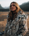 Woman wearing SpiritHoods Best Selling Hooded Wolverine Faux fur coat in a Montana mountainous landscape. Easy Halloween Costume Ideas and Halloween Outfits. Fall Fashion for Women.