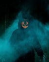 A Man wearing SpiritHoods Black Panther Classic Fake Fur Jacket in the woods at night with smoke coming up, wearing a light up red mask. Easy Halloween Costume Ideas for Men