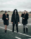 SpiritHoods Black Wolf Hooded Faux Fur Coat with a man standing on a football field wearing a halloween disco inspired mask with the black wolf hood on staring at the camera, two females are next to him wearing black wolf coats with the hoods off, looking at the camera