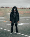 Man wearing SpiritHoods Black Wolf Hooded Faux Fur Jacket on a open field, with the hood up, wearing a mask with mirrors on it, staring at the camera. Easy Halloween Costume Ideas for Men