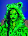 Woman wearing a neon green SpiritHoods Leopard Faux Fur Coat with a hood and leopard ears, with neon green and black face paint against a blue background. Easy Halloween Costume Ideas. Animal Lovers Halloween Outfit
