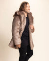 Man wearing a brown faux fur coat, with the hood off, and he strolls forward, smiling, holding the lapel of the plush SpiritHoods Italian Wolf Faux Fur Jacket