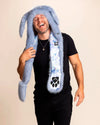 A laughing man wearing a blue bunny fake fur hood with a paw print design on a beige background. Festival and rave-ready faux fur hood with pocket.