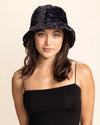 Woman wearing a black furry leopard print bucket hat on a beige background
