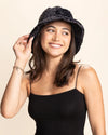 Woman smiling wearing a black leopard print bucket hat against a beige background