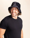 Man wearing a black animal print bucket hat and black t-shirt against a beige background