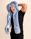 Person wearing a fuzzy blue fake fur festival hood beige background