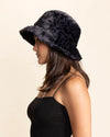Woman wearing a black fake fur bucket hat with light grey leopard print against a beige background