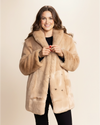 Woman wearing a beige fur free fur coat against a beige background. SpiritHoods 100% Beige Faux Fur Coat in Cougar featuring feline buttons and peacoat button closure and 4 functional pockets. SpiritHoods Fall Winter Coat Collection and Womens Fake Fur Jackets