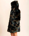Woman facing away from the camera, wearinga  SpiritHoods Camo Cat Hooded Fake Fur Coat with a hood up, and hand in one pocket, showing a hue of greens, browns, and black fake fur on a beige background
