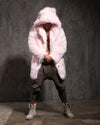 Man looking down wearing a fluffy pink hooded fake fur coat against a dark textured wall.