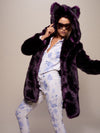 Girl in dark purple fake fur Midnight Wolf Coat with hood and ears upeaning to one side with one hand at her ear like she's on the phone and the arm stretched out to the side.