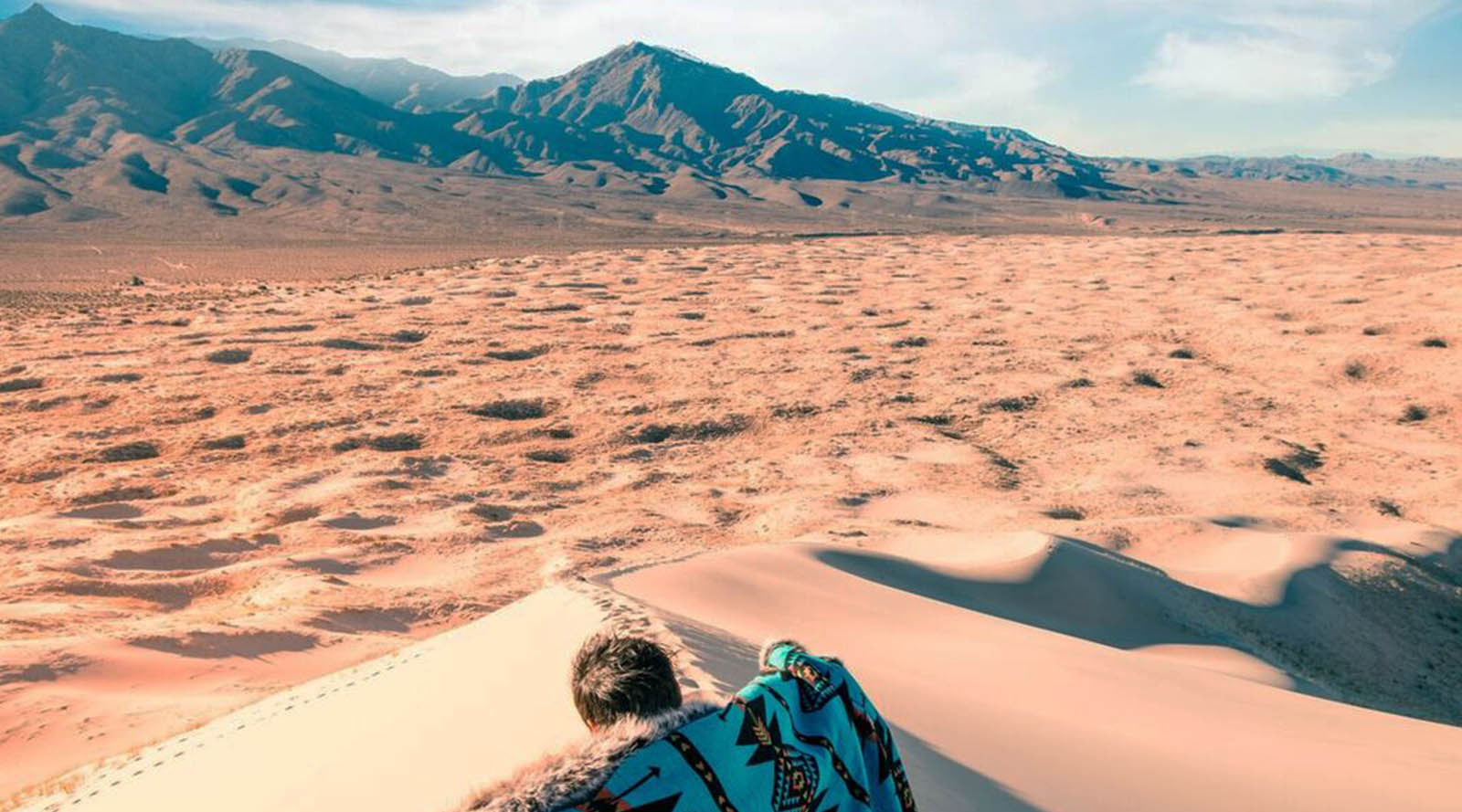 person with faux fur throw overlooking desert