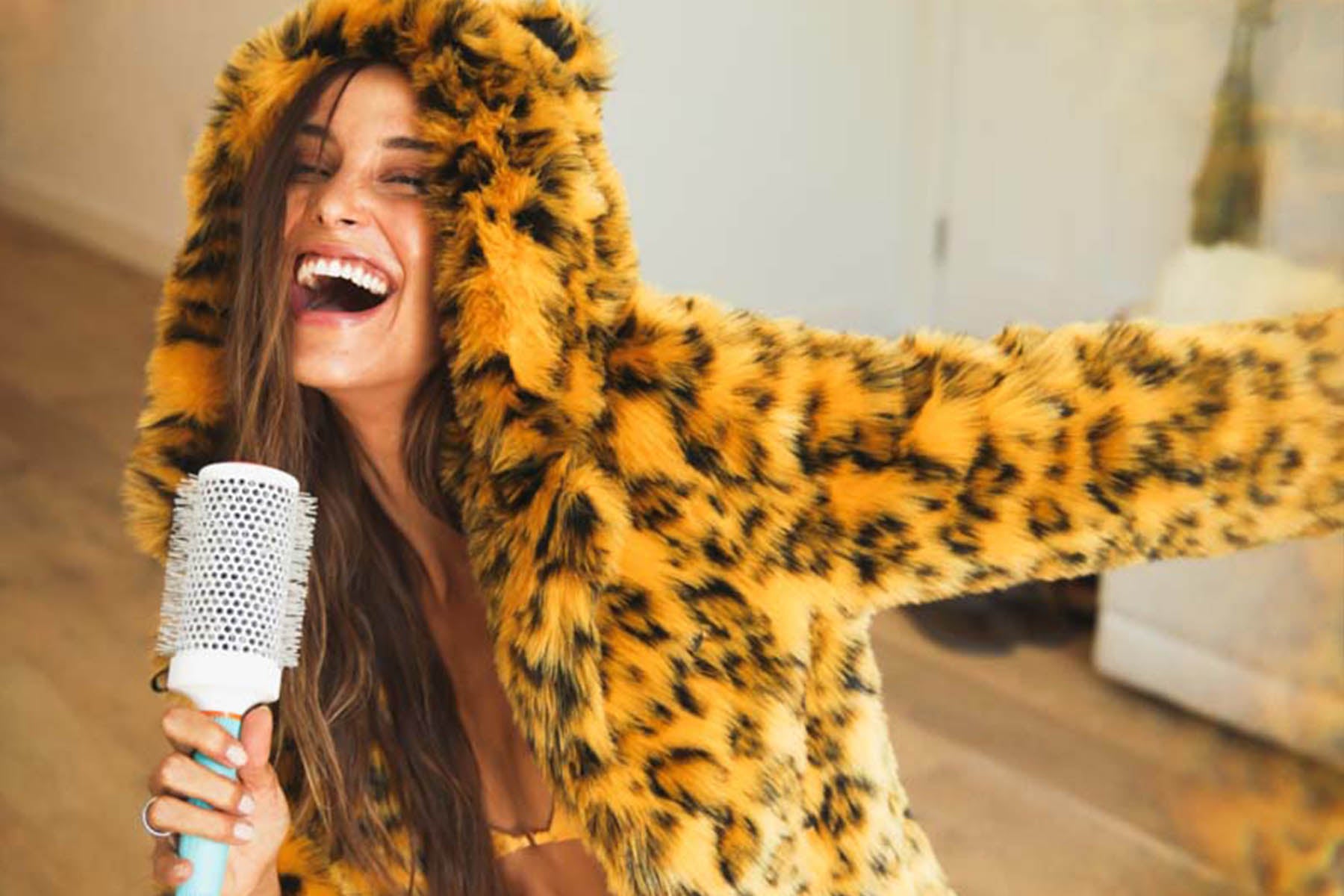woman wearing leopard faux fur coat singing into hairbrush