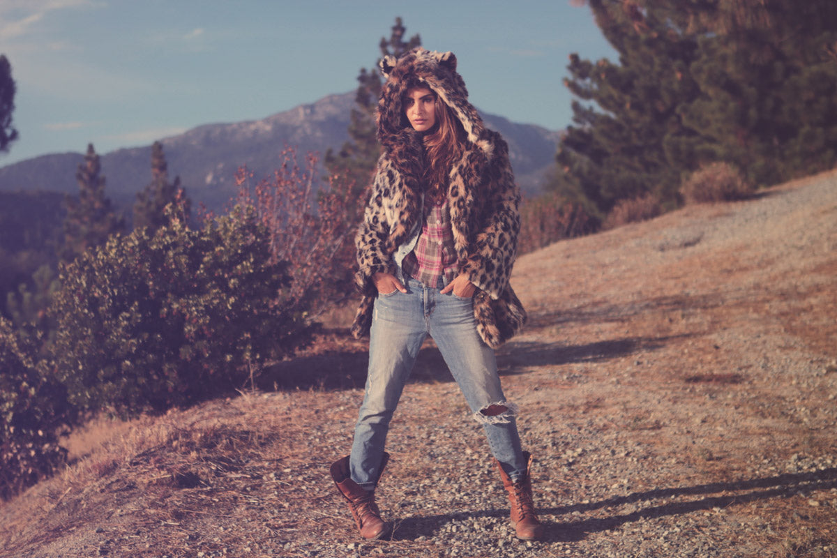person standing in forest wearing jeans and faux fur coat