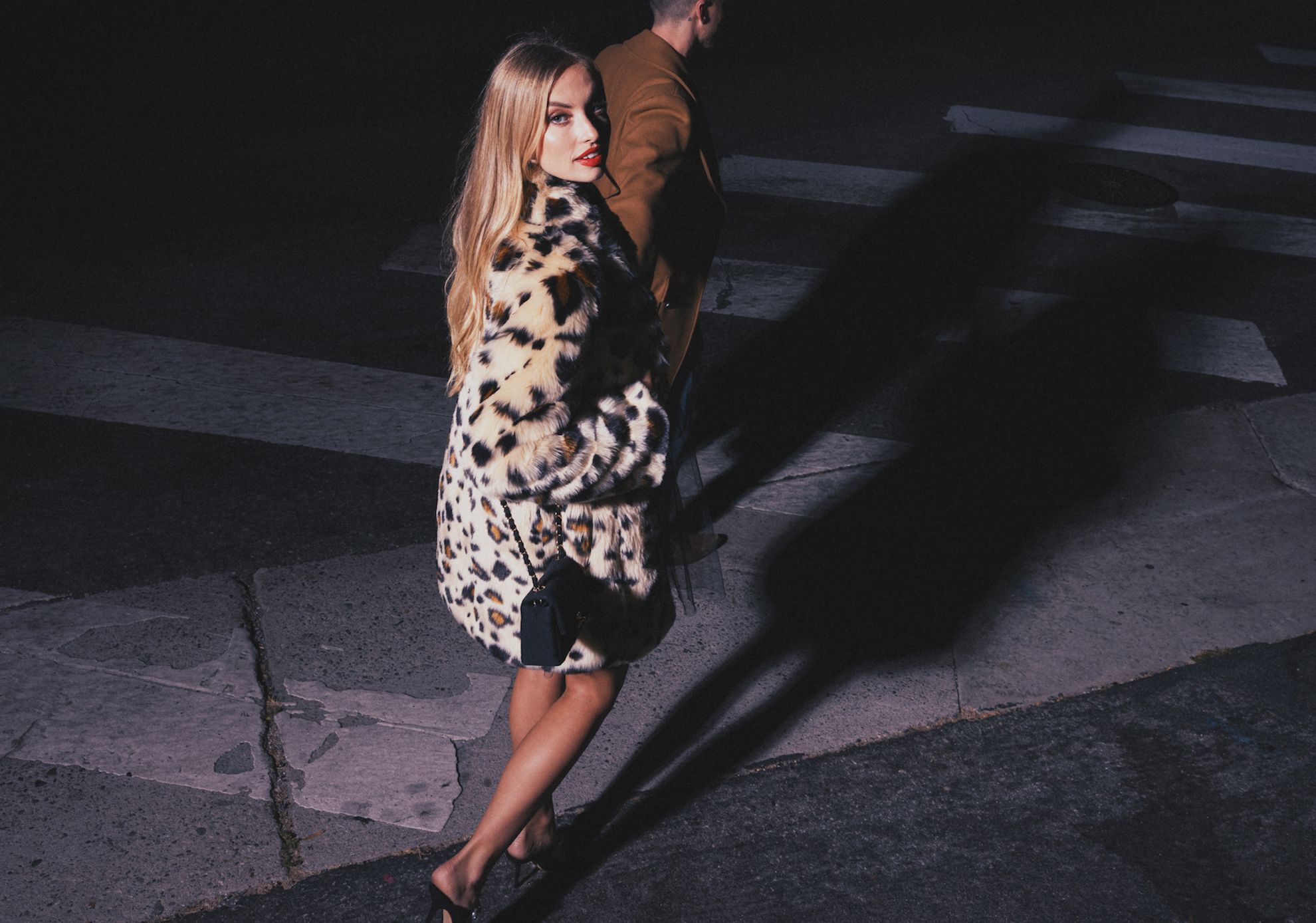 A woman is walking down the street wearing a SpiritHoods leopard print faux fur coat.