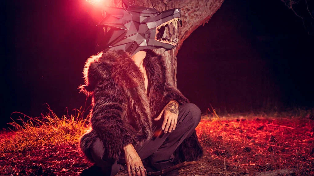 An image of a man wearing the Spirithoods grey wolf faux fur coat wearing a mask and sitting by a tree.
