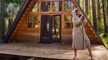 An image of a woman wearing the SpiritHoods wolverine faux fur robe outside a cabin.