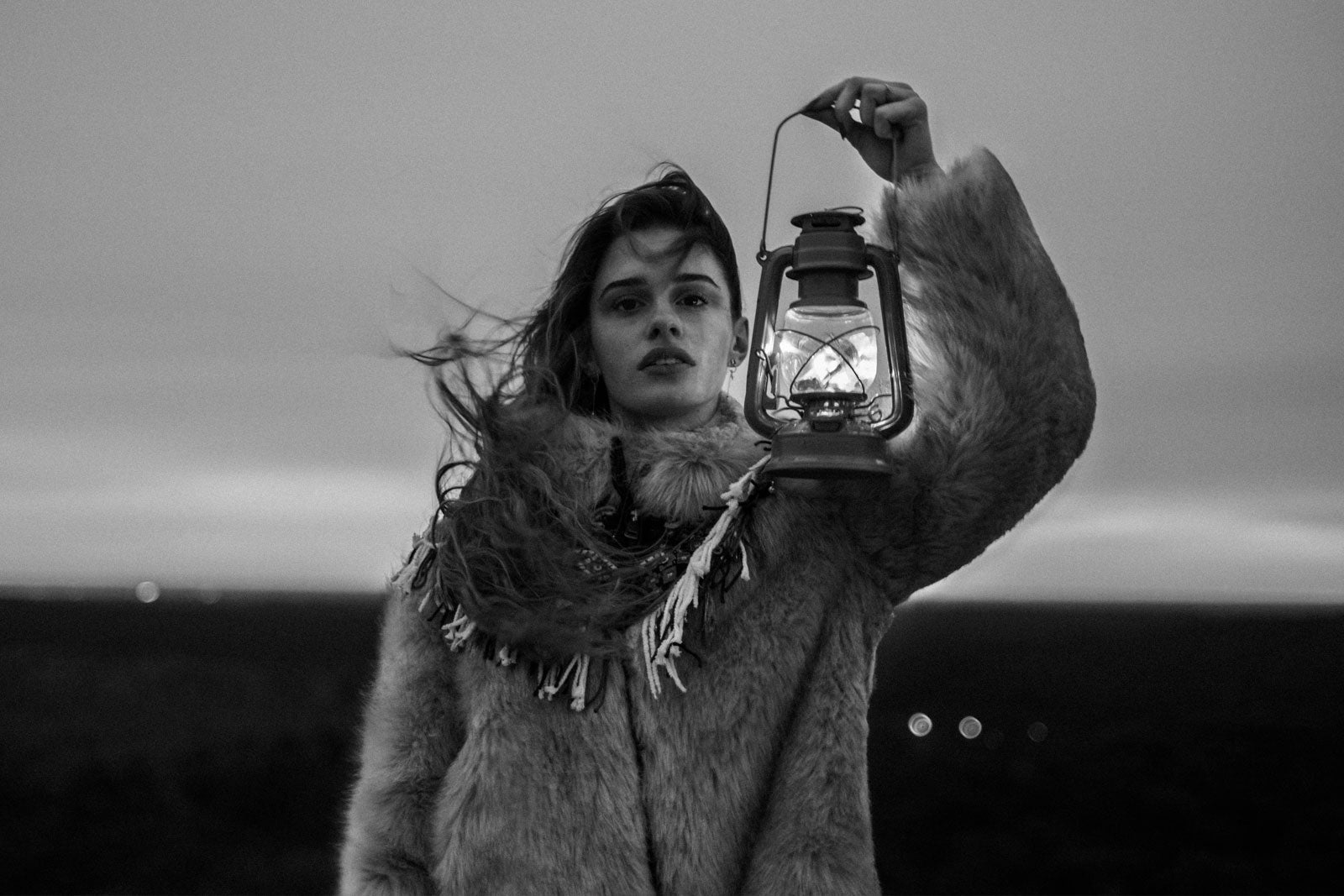 woman wearing faux fur holding lantern in black and white