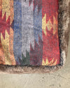 Multicolored patterned pet bed with fur border on a concrete floor