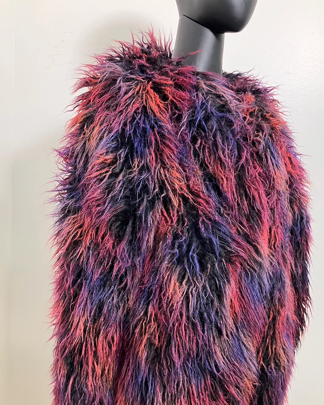 Multicolored fake fur bomber jacket on a mannequin against a plain background