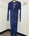 A long-sleeve, full-length jumpsuit with a blue and purple abstract pattern, hanging on a black hanger against a plain off-white wall.