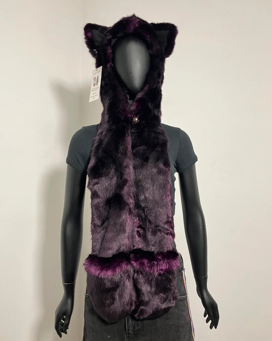 A dark purple faux fur hooded vest with cat ears and a matching furry collar trim, displayed on a black mannequin torso against a plain light background.