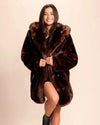 SpiritHoods Women's Hooded Faux Fur Coat in plush brown wolf, model smiling looking at the camera with one leg up.
