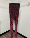 Magenta pink and black leopard print leggings hanging on a clear plastic hanger against a plain white wall.