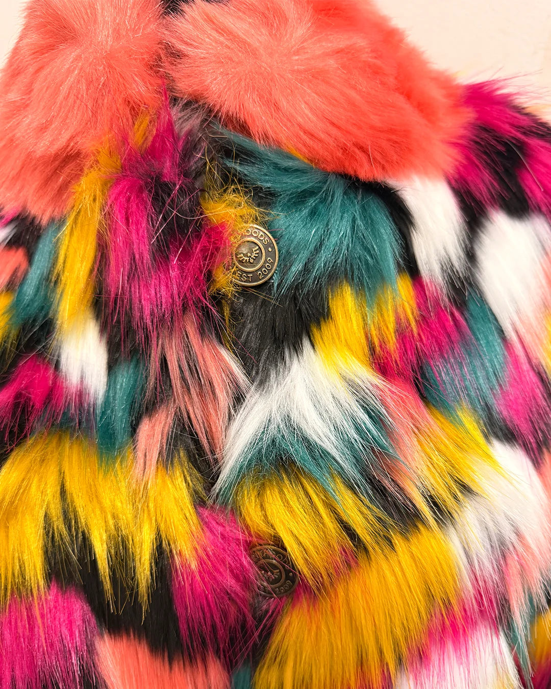 Close-up of a multicolored fake fur jacket with a button detail.