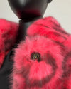 Close-up of a neon pink faux fur coat on a mannequin with a plain background