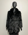 Mannequin wearing a dark fur coat against a plain background