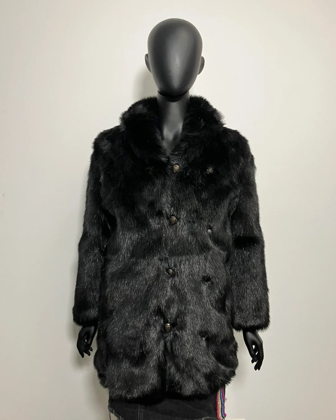 Mannequin wearing a dark fur coat against a plain background