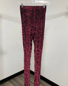Red and black leopard print leggings hanging on a clear plastic hanger against a plain white wall.