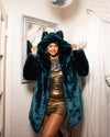 A Woman smiling at the camera, wearing a SpiritHoods Royal Wolf Luxury Blue Faux Fur Coat with an oversized hood with ears, she is holding the sides of the hood while looking into the camera and smiling. 100% Fake Fur Coats for Women. Top Rated Womens Fall/Winter Faux Fur Coats and Clothing
