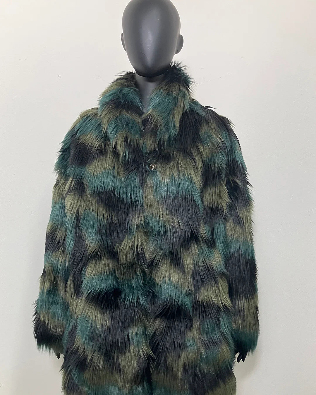 Mannequin wearing a green and black fake fur coat on a white background