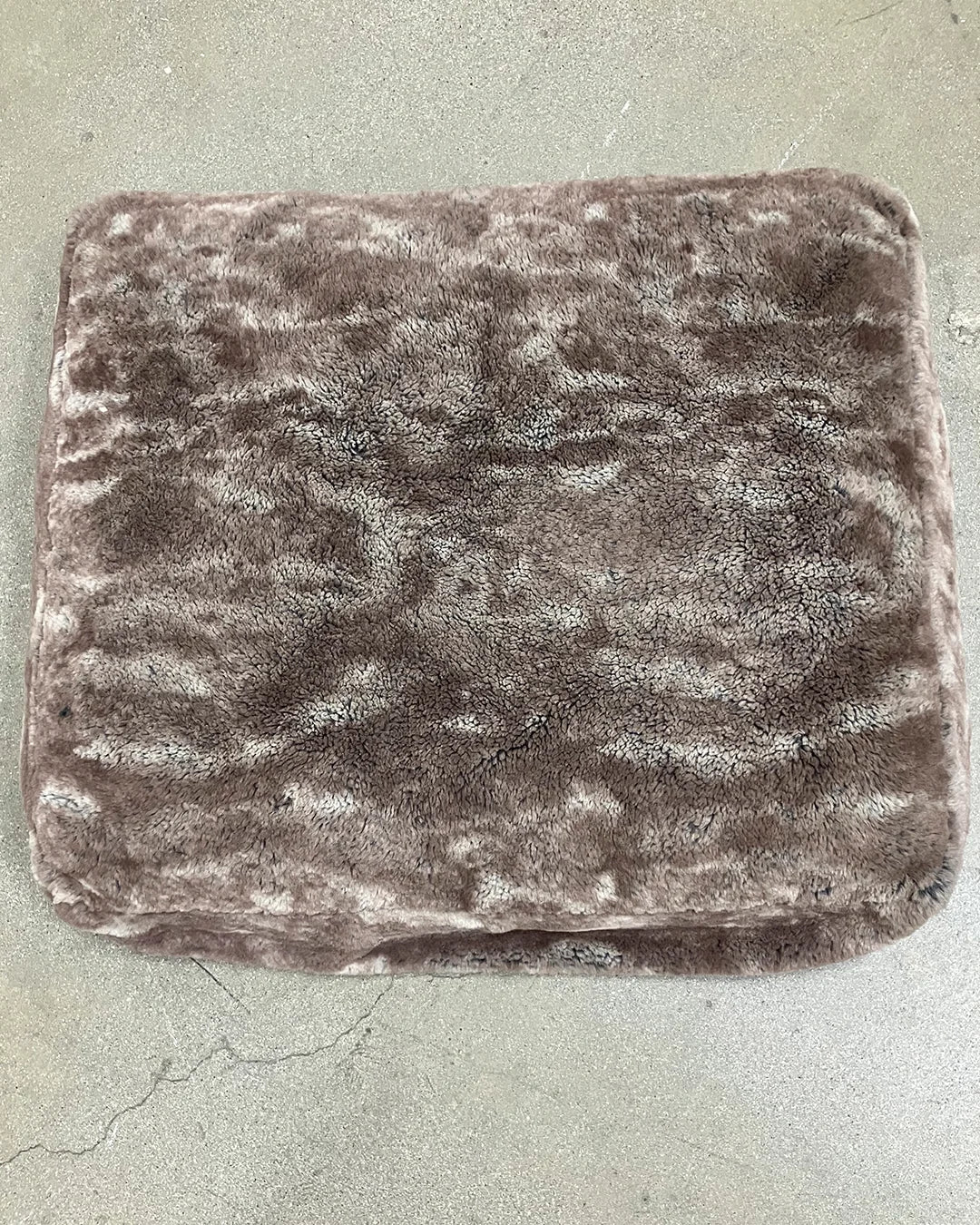 Textured brown pet bed cushion on a concrete floor