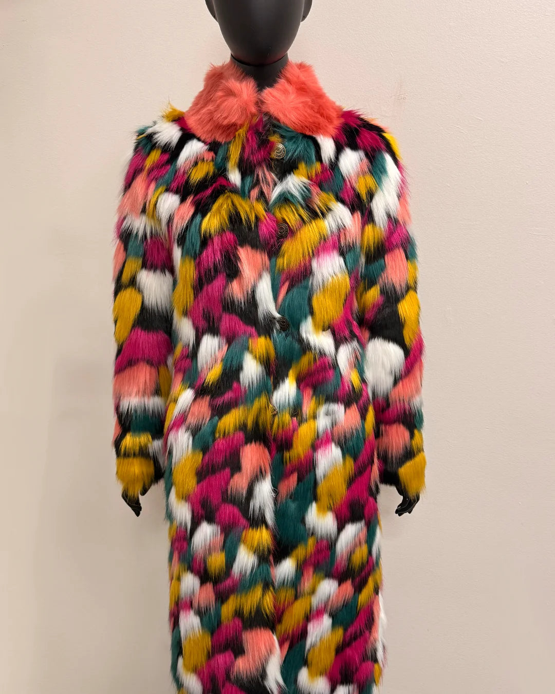 Multicolored fale fur coat with a vibrant pattern on a mannequin against a plain background