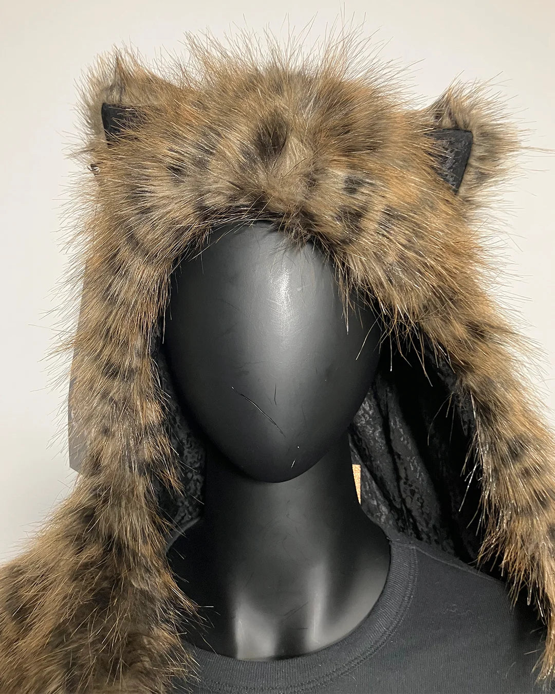 Faux fur hooded coat with ears on a mannequin head against a neutral background