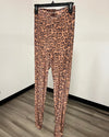 Tan and brown leopard print velvet leggings on a black hanger in front of a plain white wall.