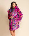 Woman wearing a colorful SpiritHoods neon pink leopard print fake fur coat against a beige background. SpiritHoods Made to Order Fall Faux Fur Coats and Custom Made Fake Fur Festival Jackets 