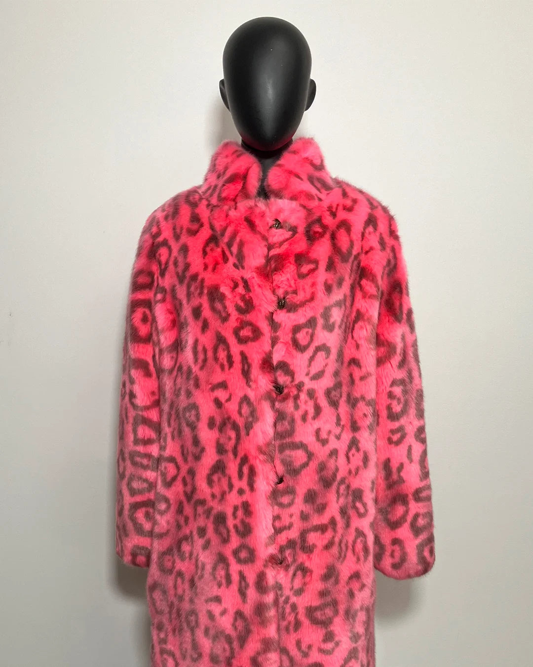Mannequin wearing a bright pink coat with black leopard print pattern on a white background