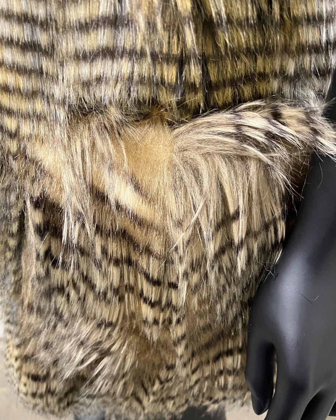 close-up photo of the pocket fake fur and opening of the outer pocket on the vest, show casing a darker brown hawk inspired fake fur. SpiritHoods Online Sample Sale Style: Hooded Faux Fur Vest in Alaskan Hawk - Size Medium.