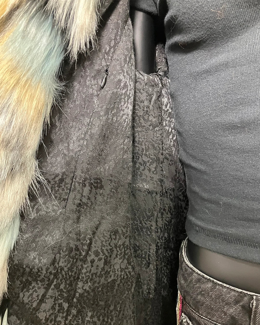 Close-up of a textured  snakeskin lining fabric surface with faux fur trim and a person wearing a gray sweater.