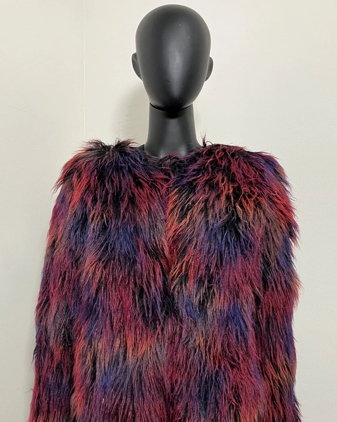 Multicolored fake fur jacket on a mannequin against a plain background